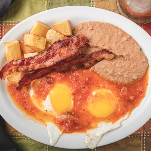 Huevos rancheros with two fried eggs, salsa, bacon, home fries, and refried beans.