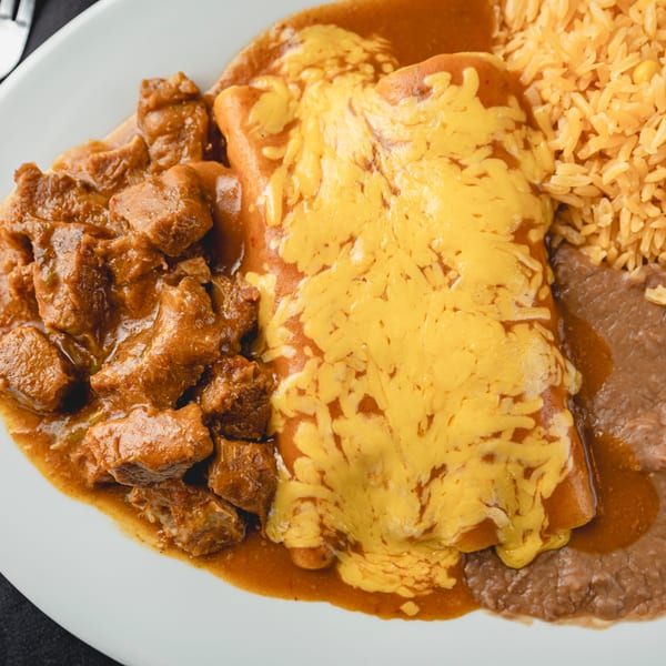 A plate of Mexican food with chili Colorado, cheese enchiladas, rice, and refried beans.