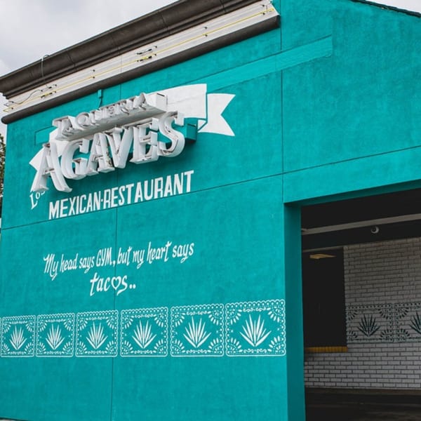 Exterior of Taqueria Los Agaves, a teal Mexican restaurant with a humorous quote and agave plant decor.