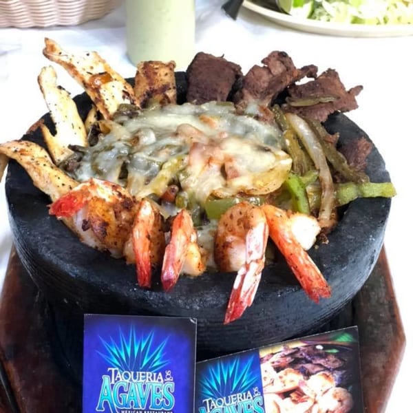 Molcajete with grilled chicken, steak, shrimp, melted cheese, and vegetables at Taqueria Los Agaves.